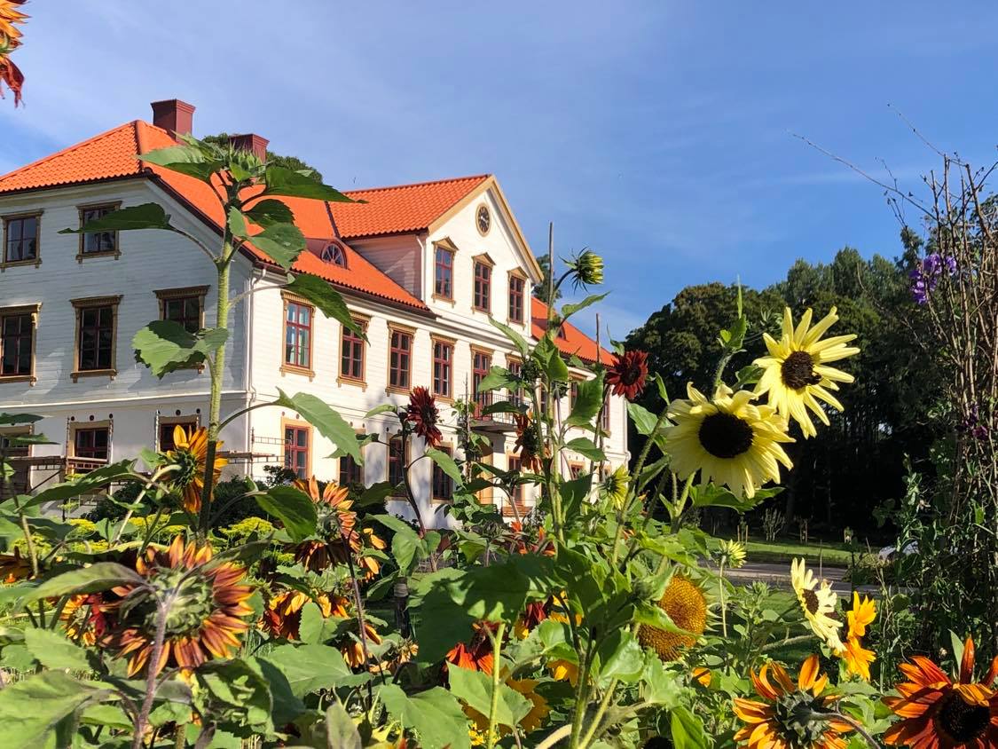 Stort vitt hus med blommor i förgrunden