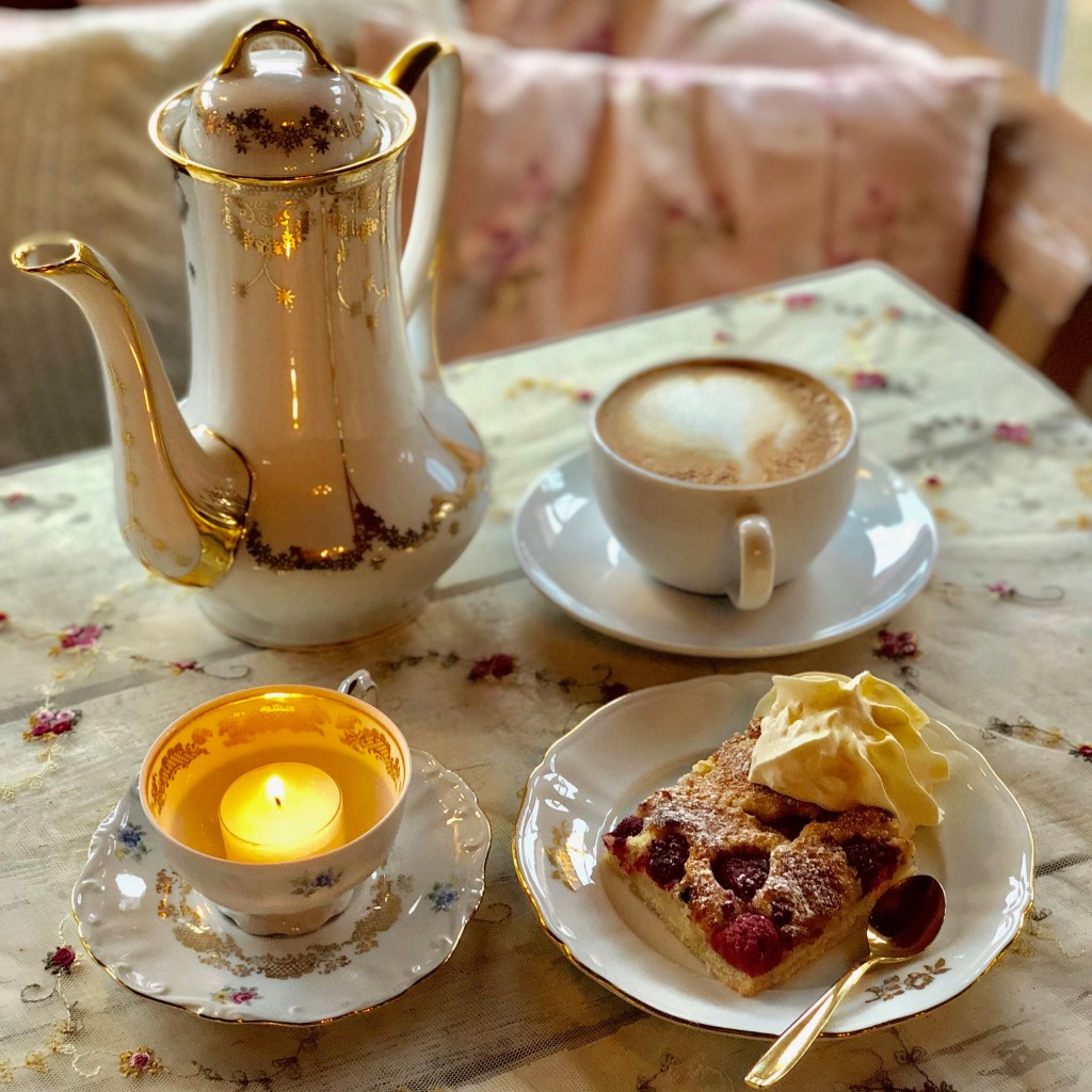 En koopp med kaffe, en kaffekanna och en kaka. 