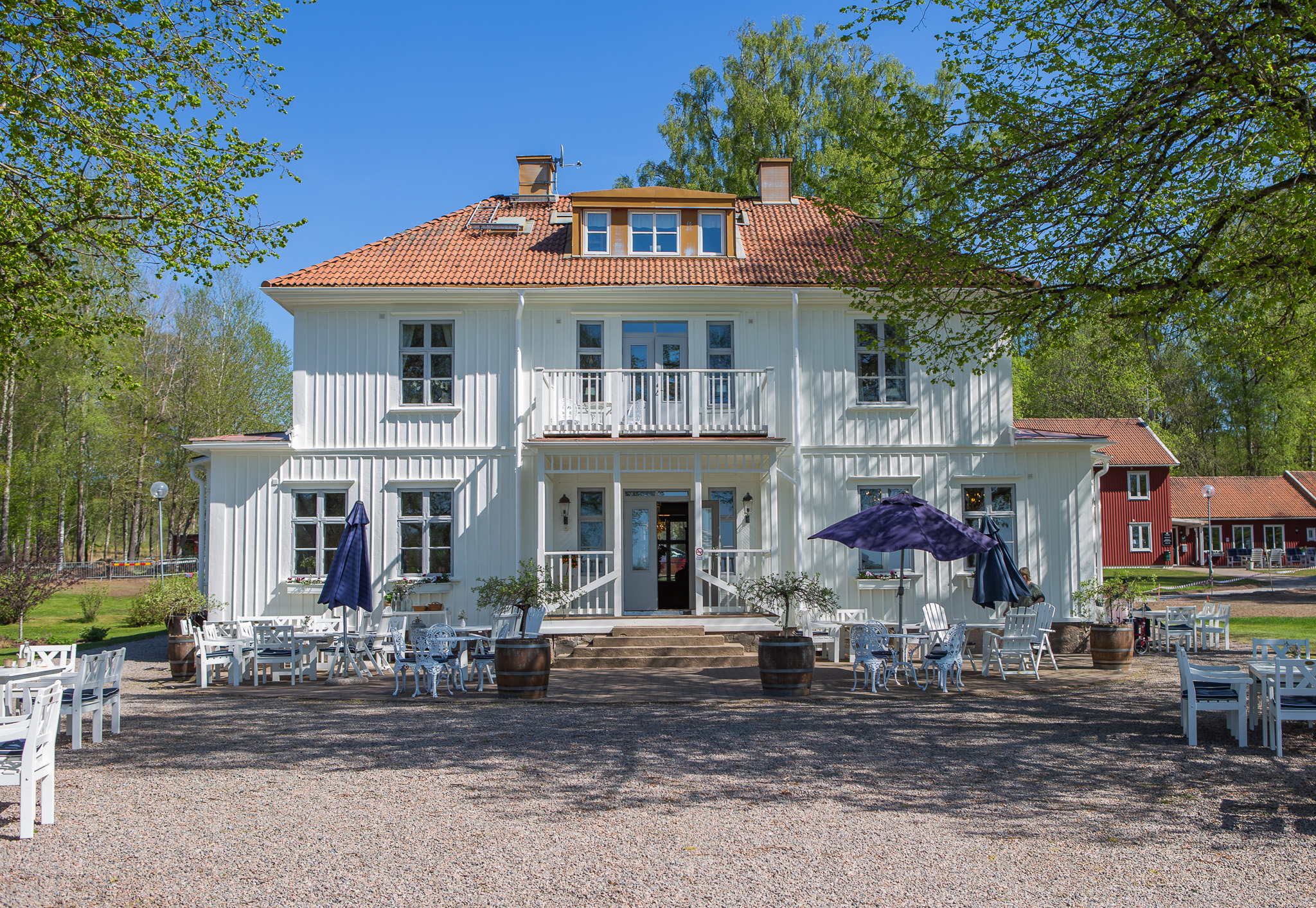 Framsidan av en vit herrgård med rött tak