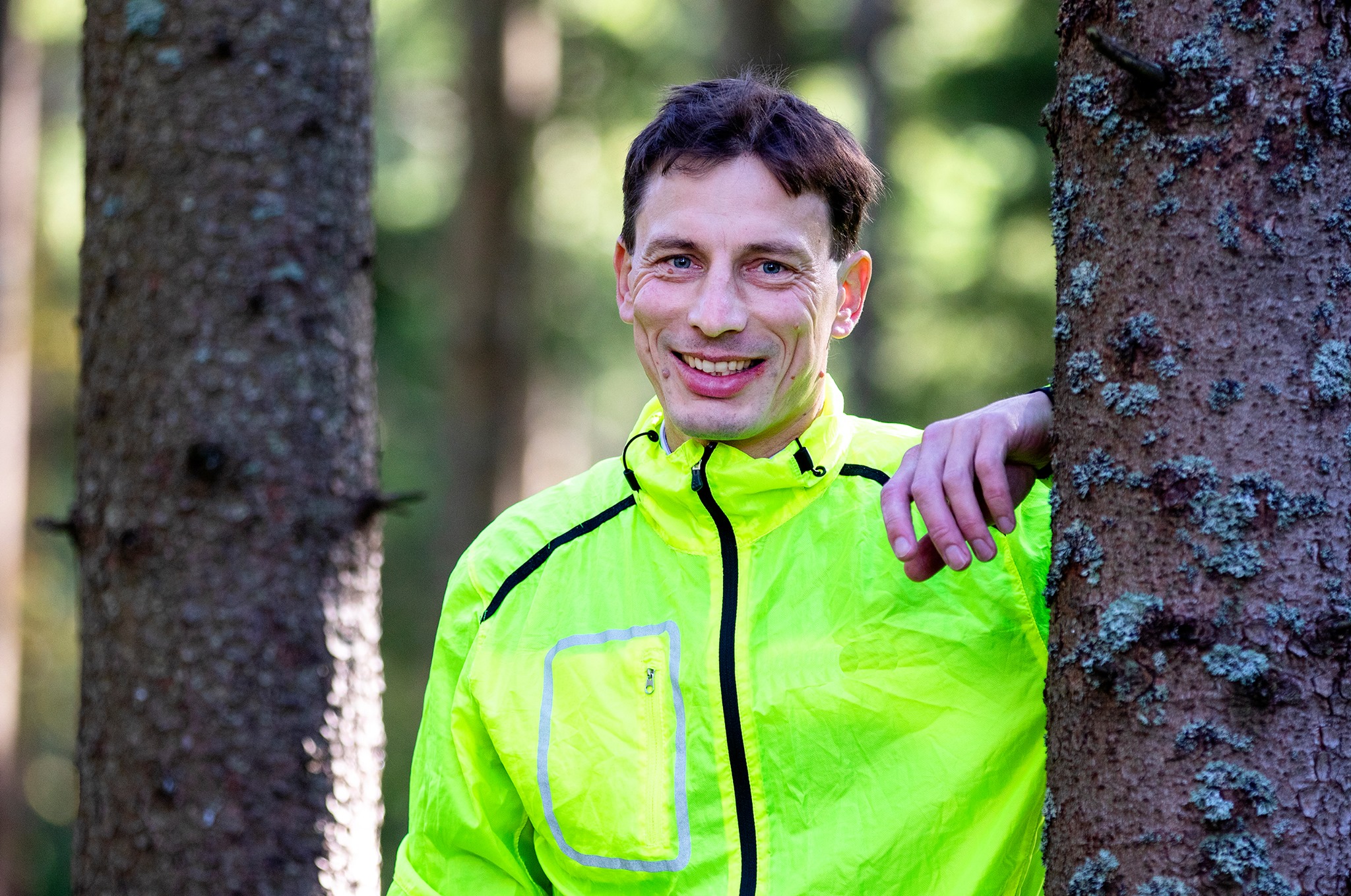 Glad kille står lutad mot ett träd.