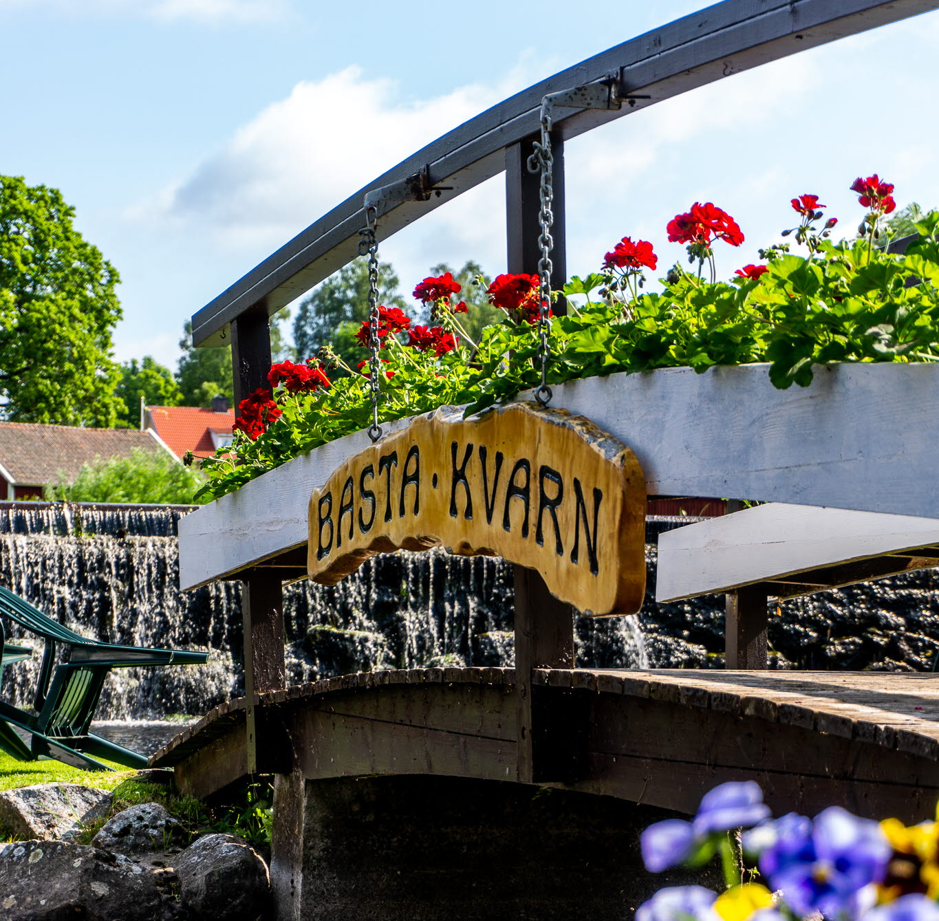 Bild på en bro vid ett kafé. Bron går ut till en liten ö i en å.