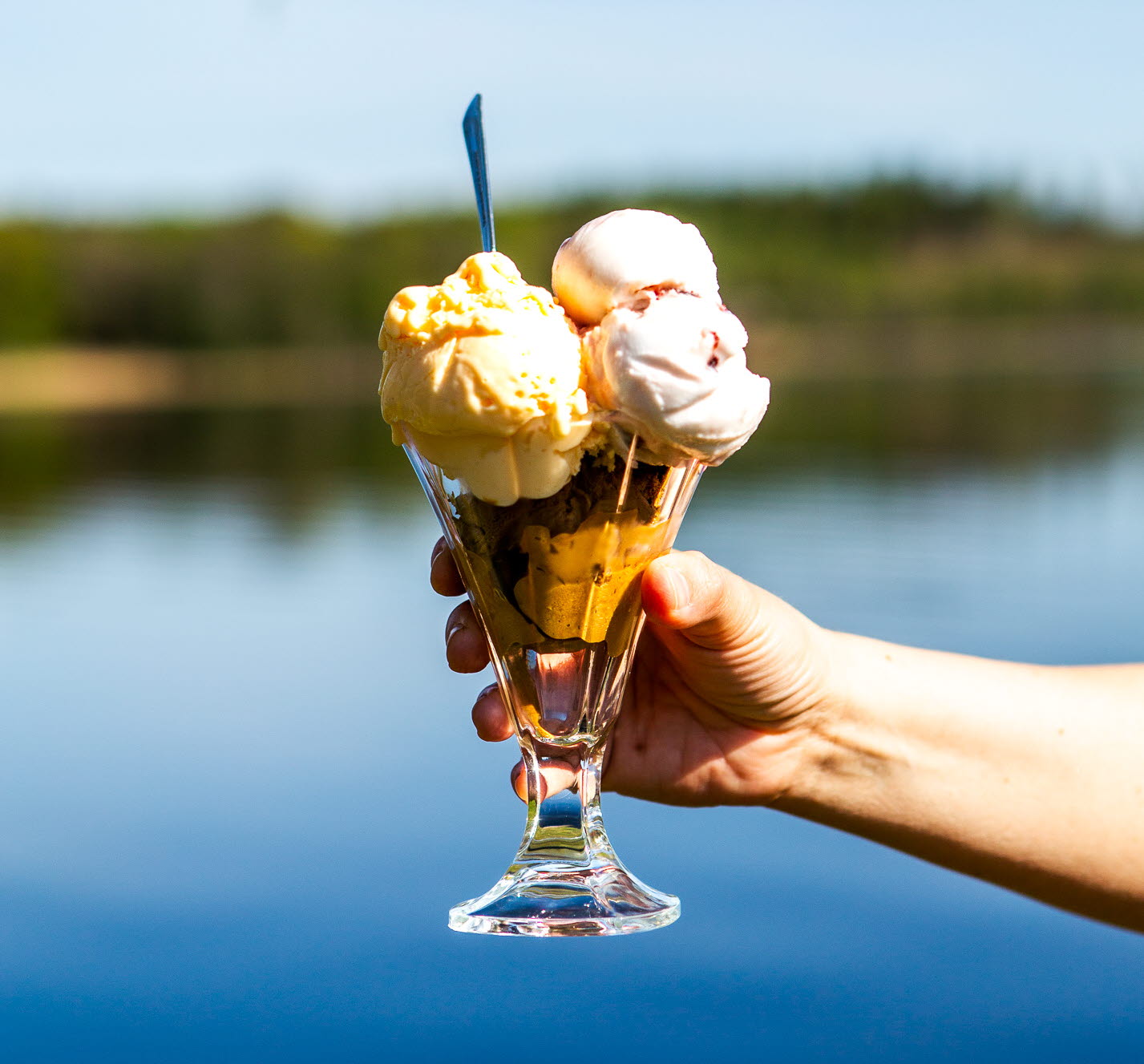 En glass hålls fram med en sjö som bakgrund