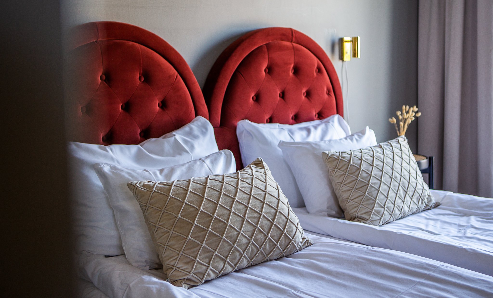 En skön hotellsäng med röd sänggavel