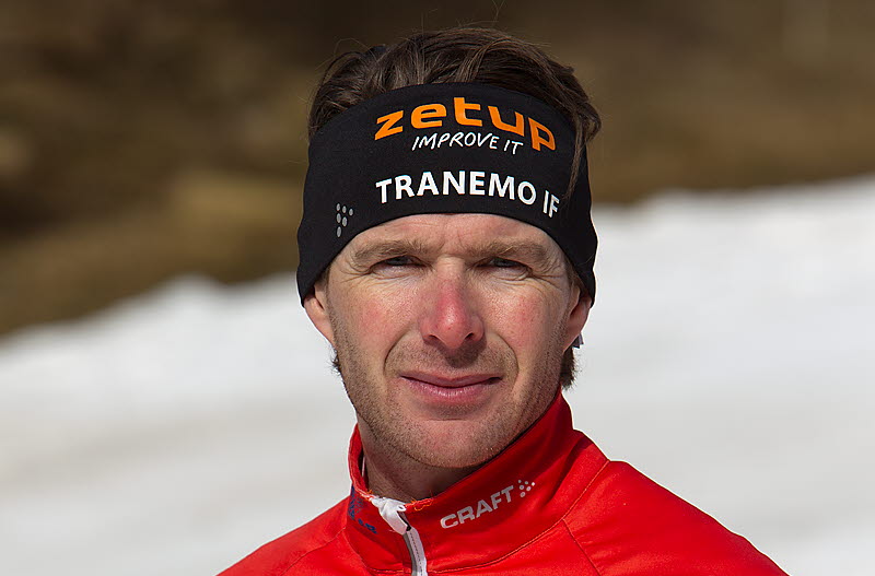 Kille i röda kläder som är instruktör i skidor