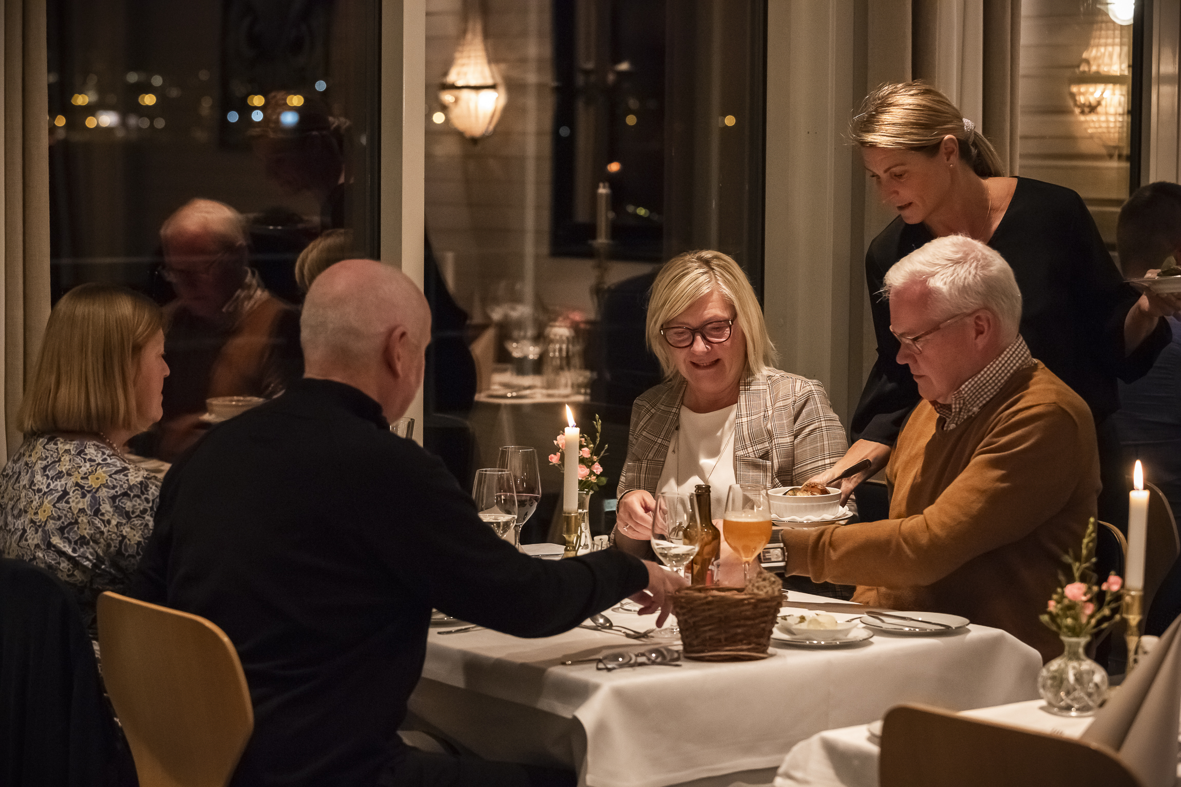 Four people sitting round a table being served