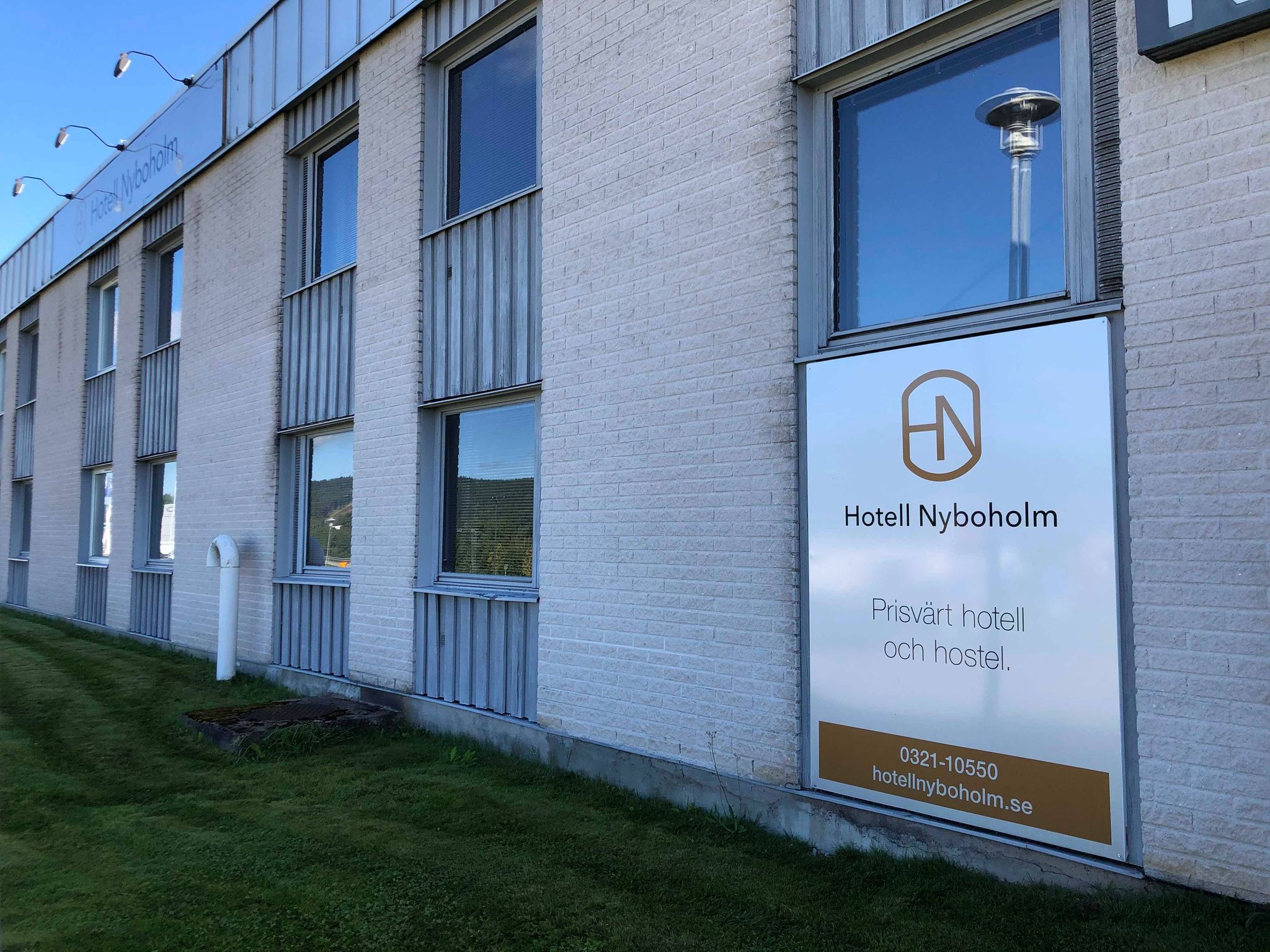 Hotellfasad i vitt tegel och grått trä