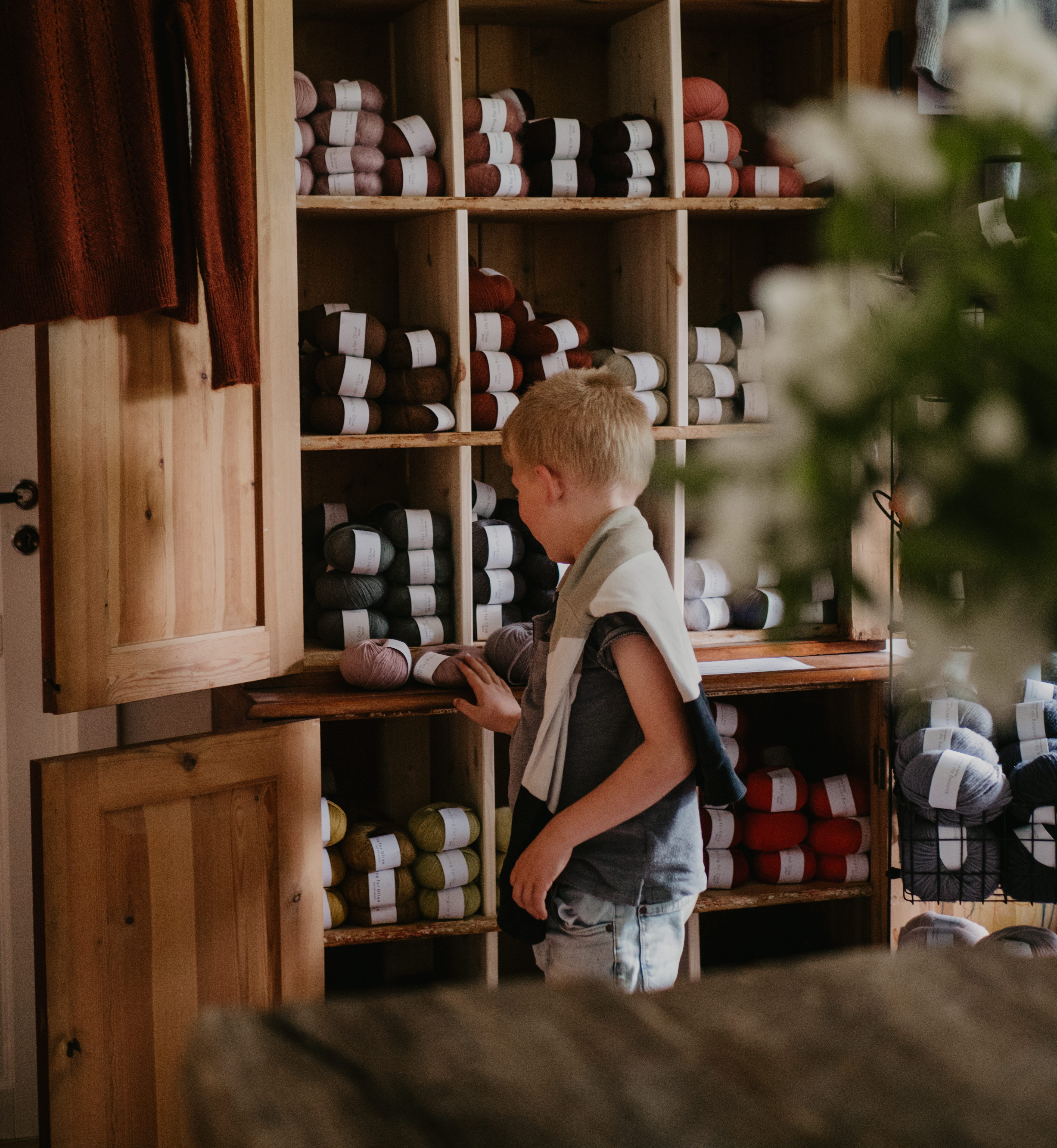 Pojke kollar på garnrullar i butik