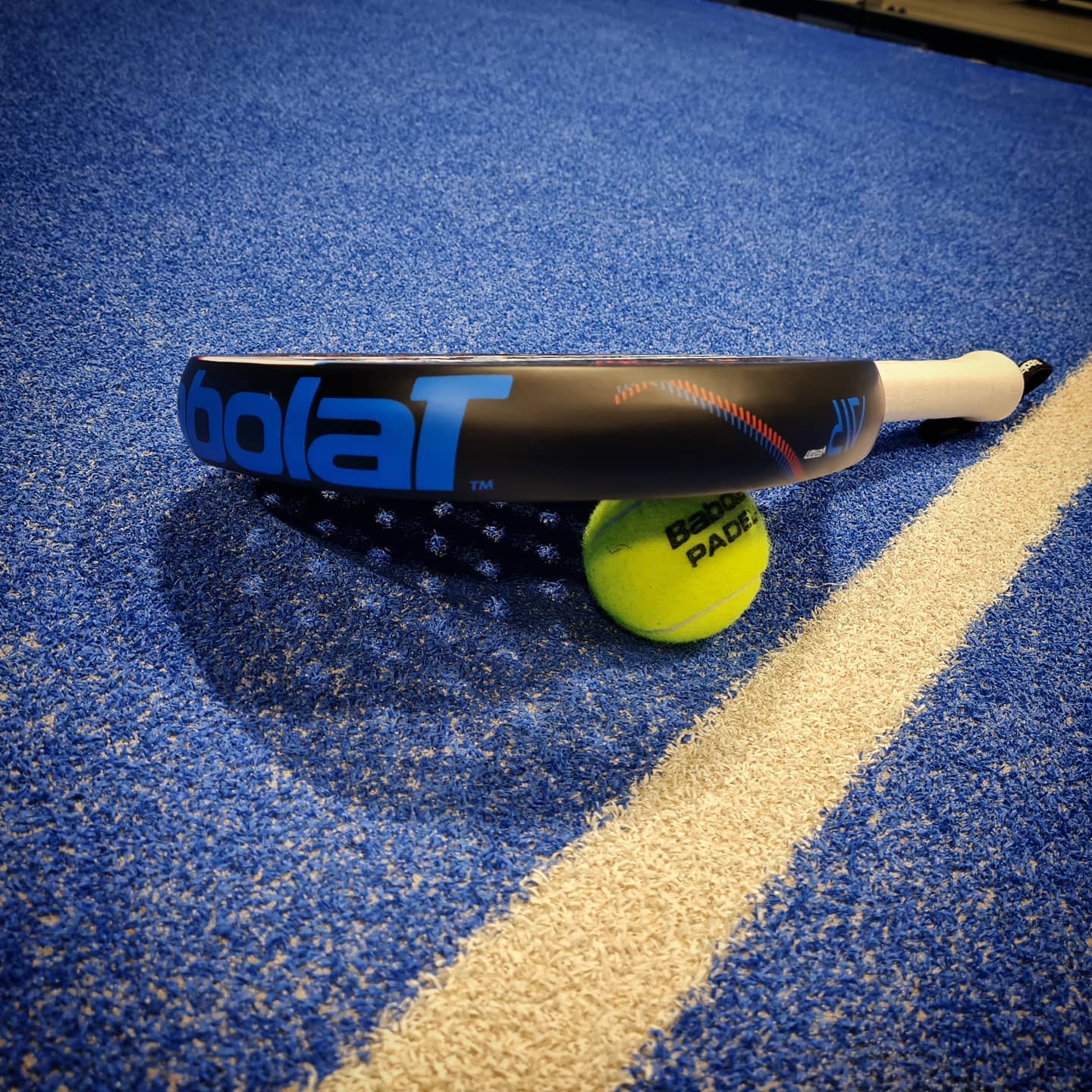 Racket och boll på blått golv