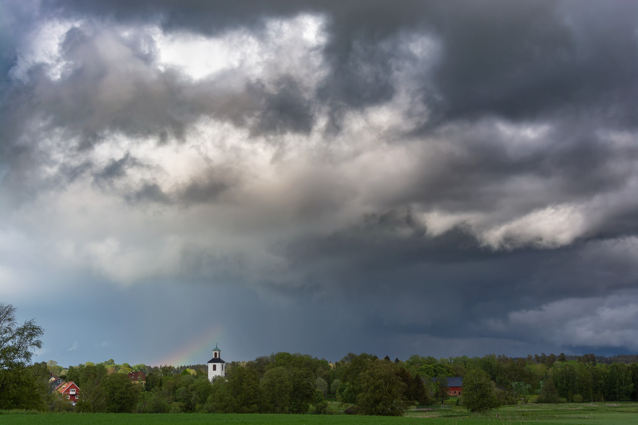 Regn med regnbåge över kyrka i Ulricehanm.