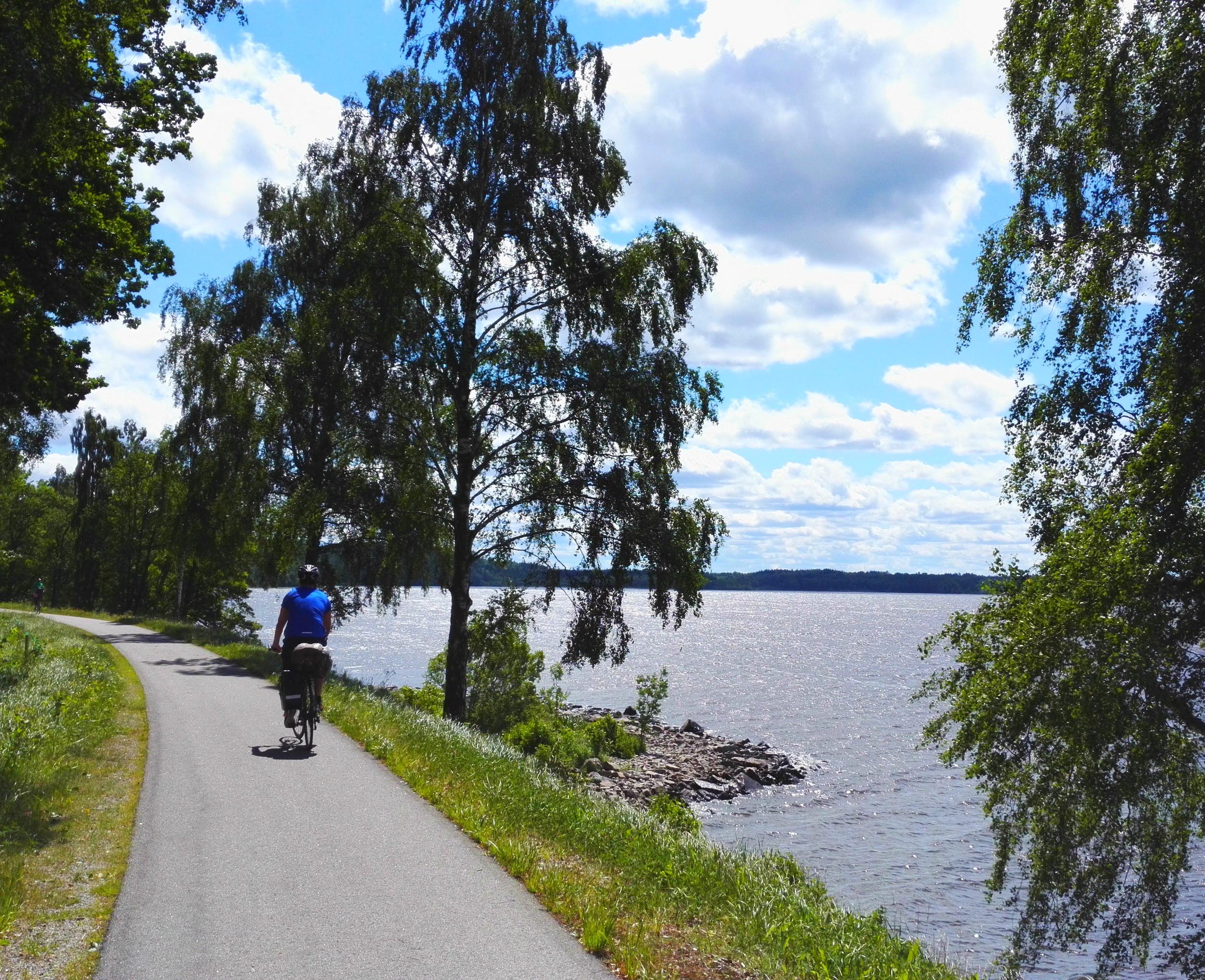 En asfalterad cykelväg strax intill en sjö