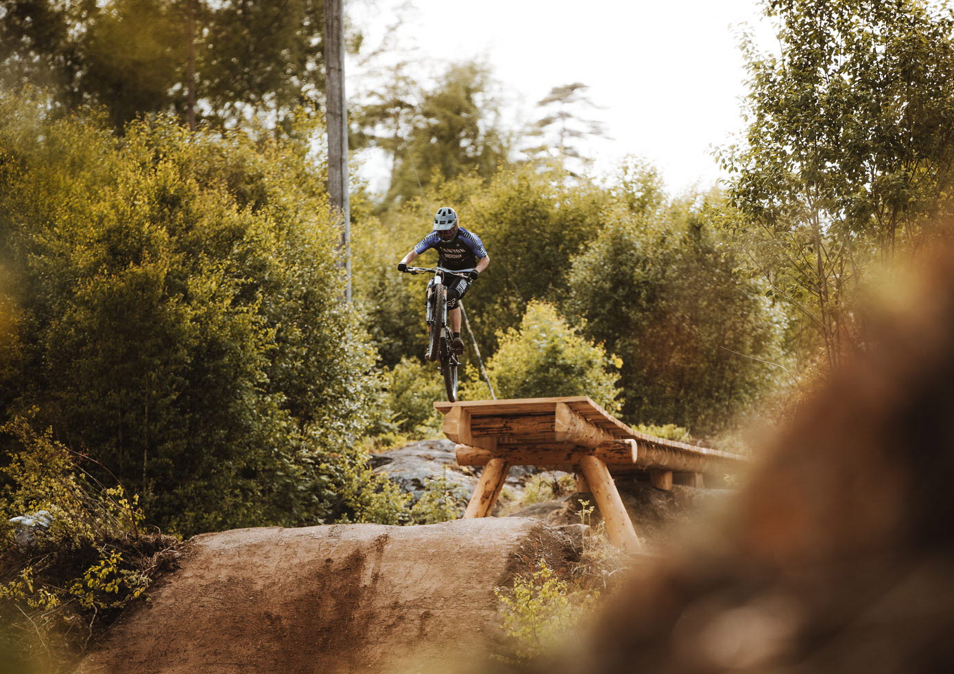 mtb åkare hoppar över gap hopp. Mtb åkaren är i luften påväg mot landning. 
