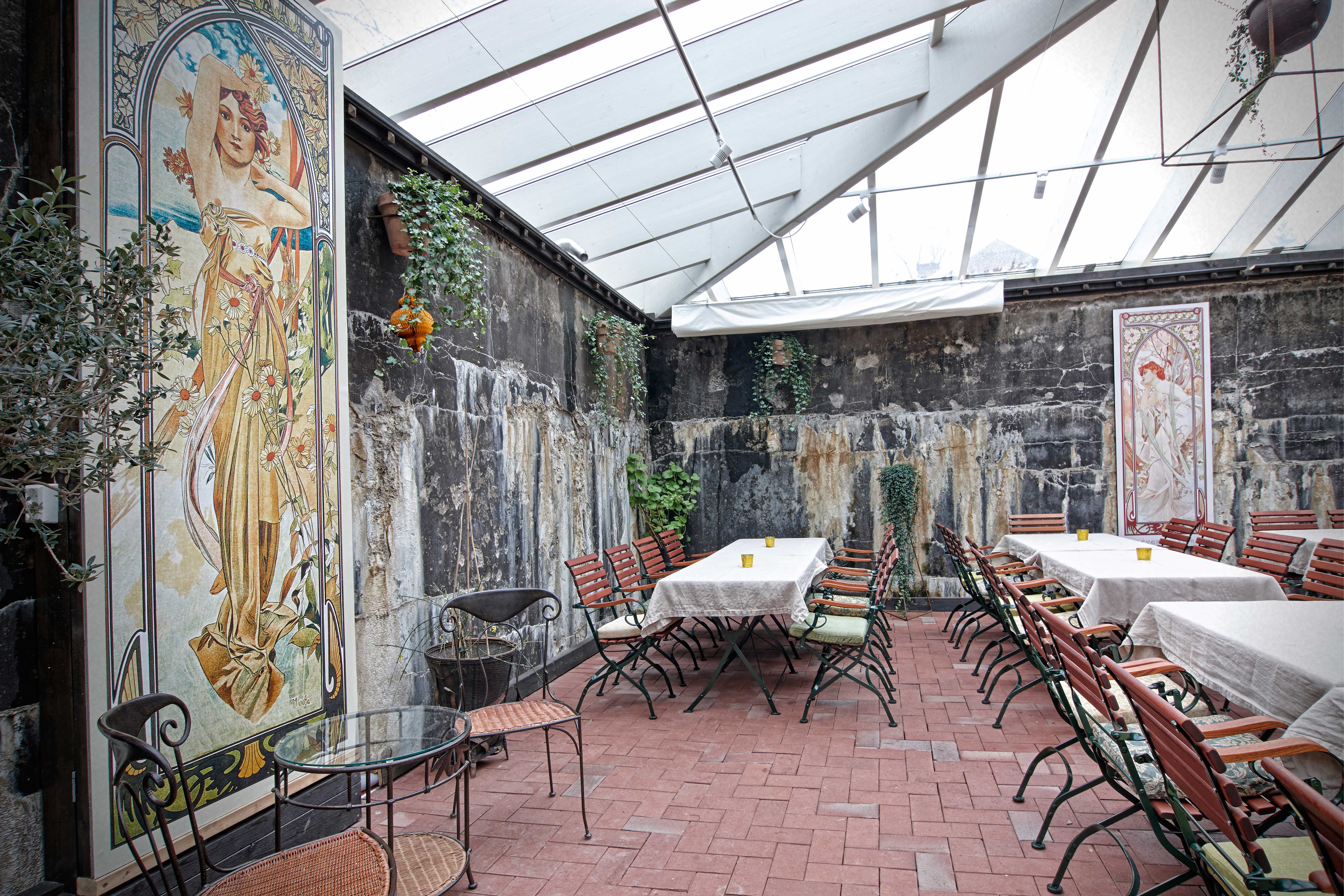 Bord och stolar i ett stenrum med vackerts målade väggar och glastak