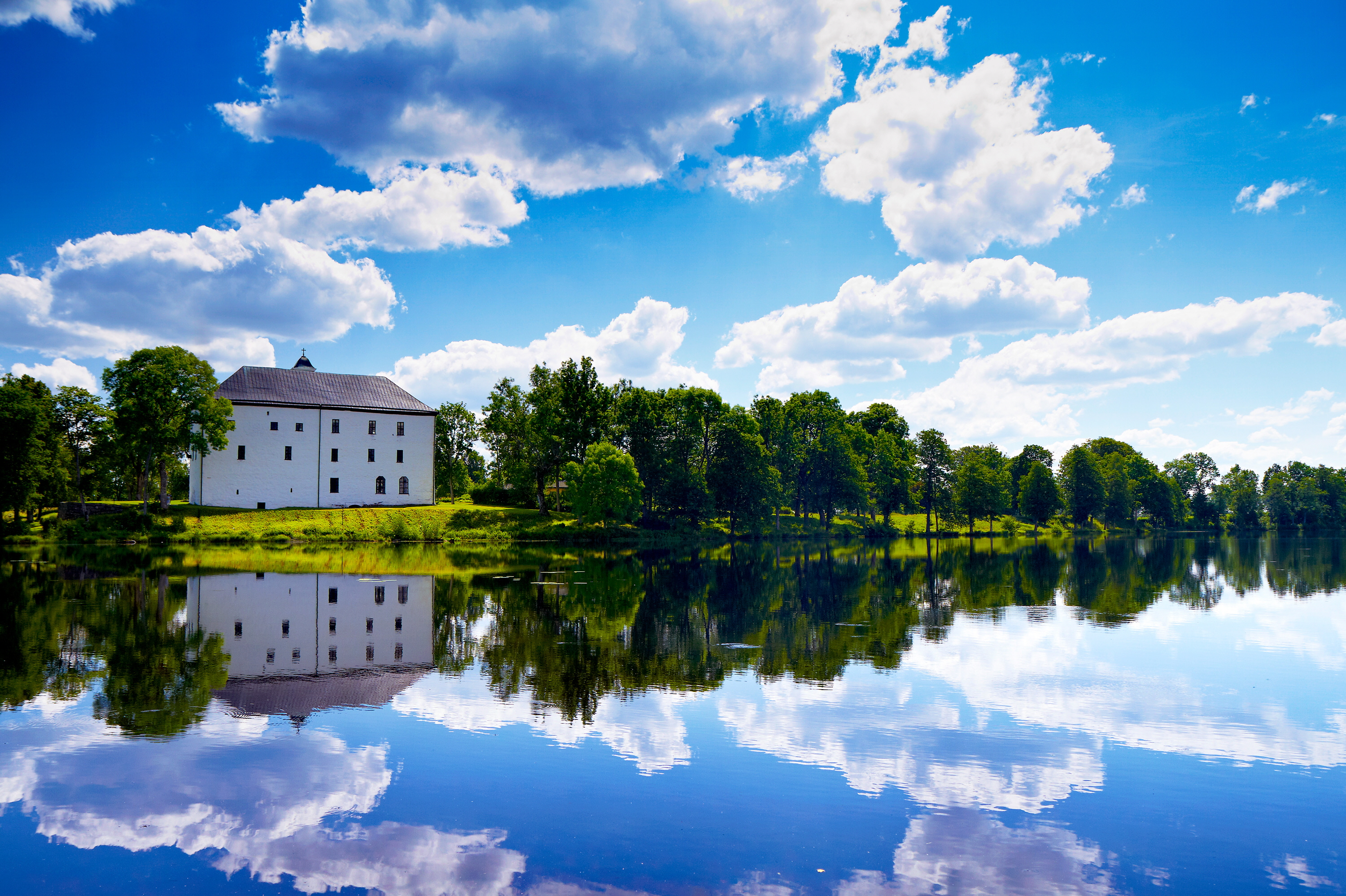 Vitt slott i grön omgivning med en sjö framför