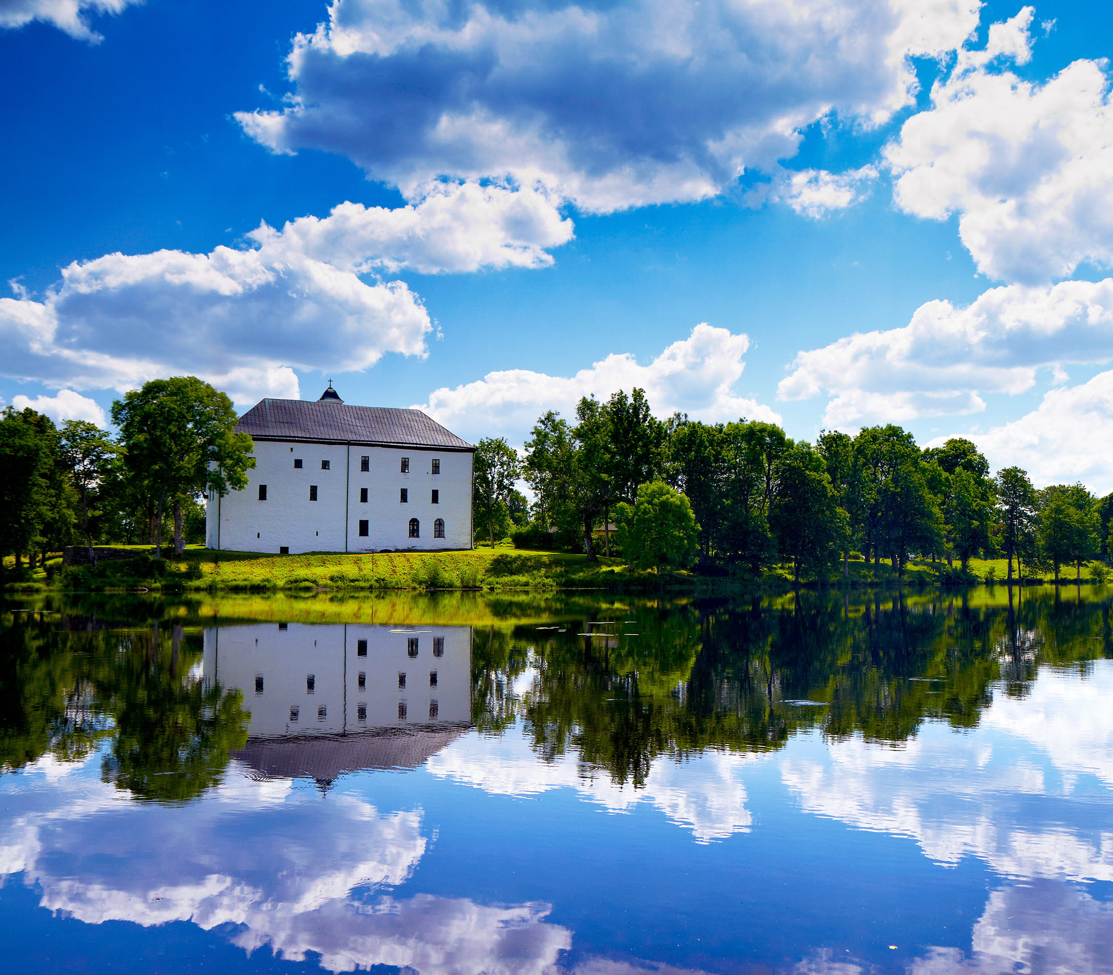 Vitt slott i grön omgivning med en sjö framför