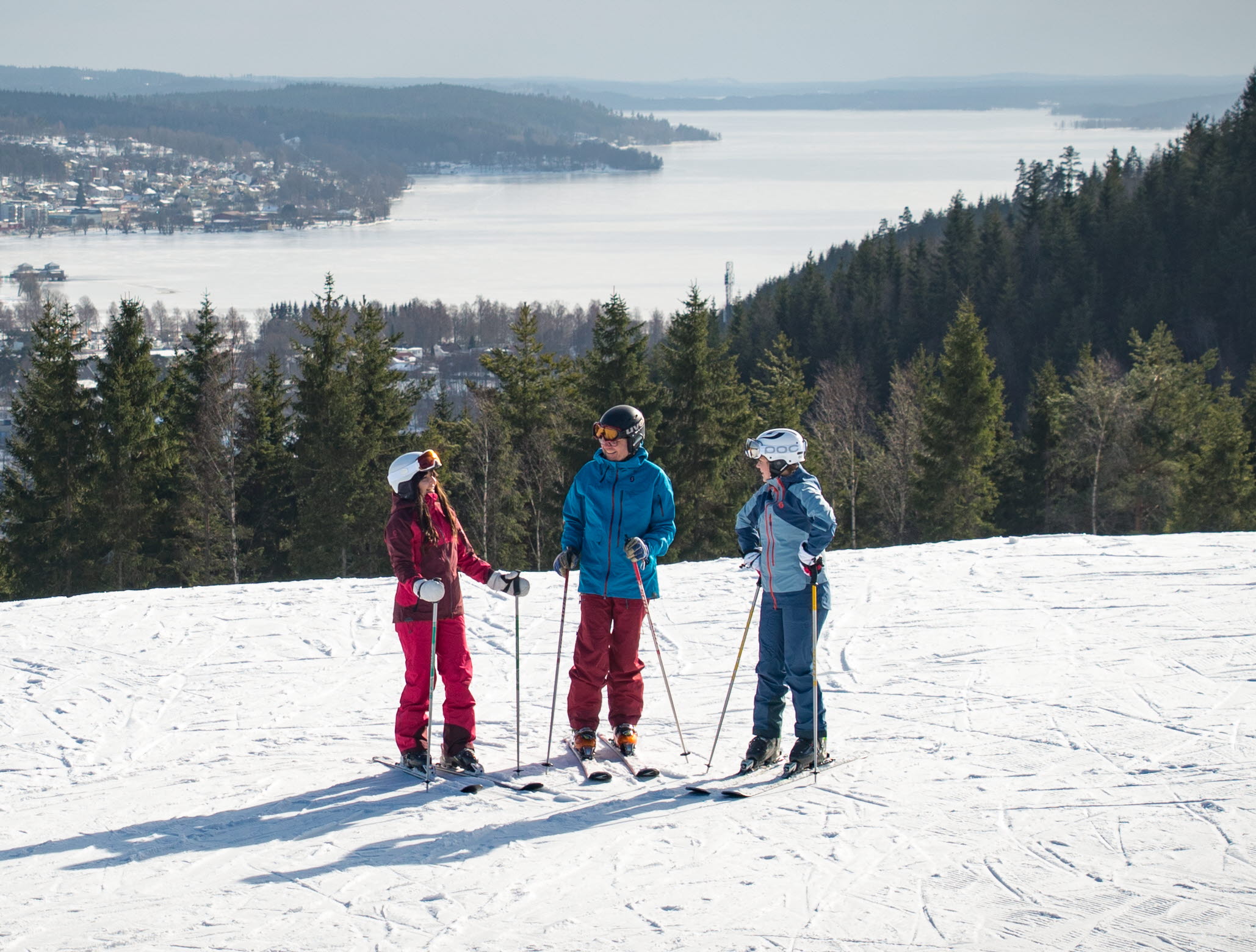 Three children in colorful clothes with skis on top of Ulricehamn Ski Center.