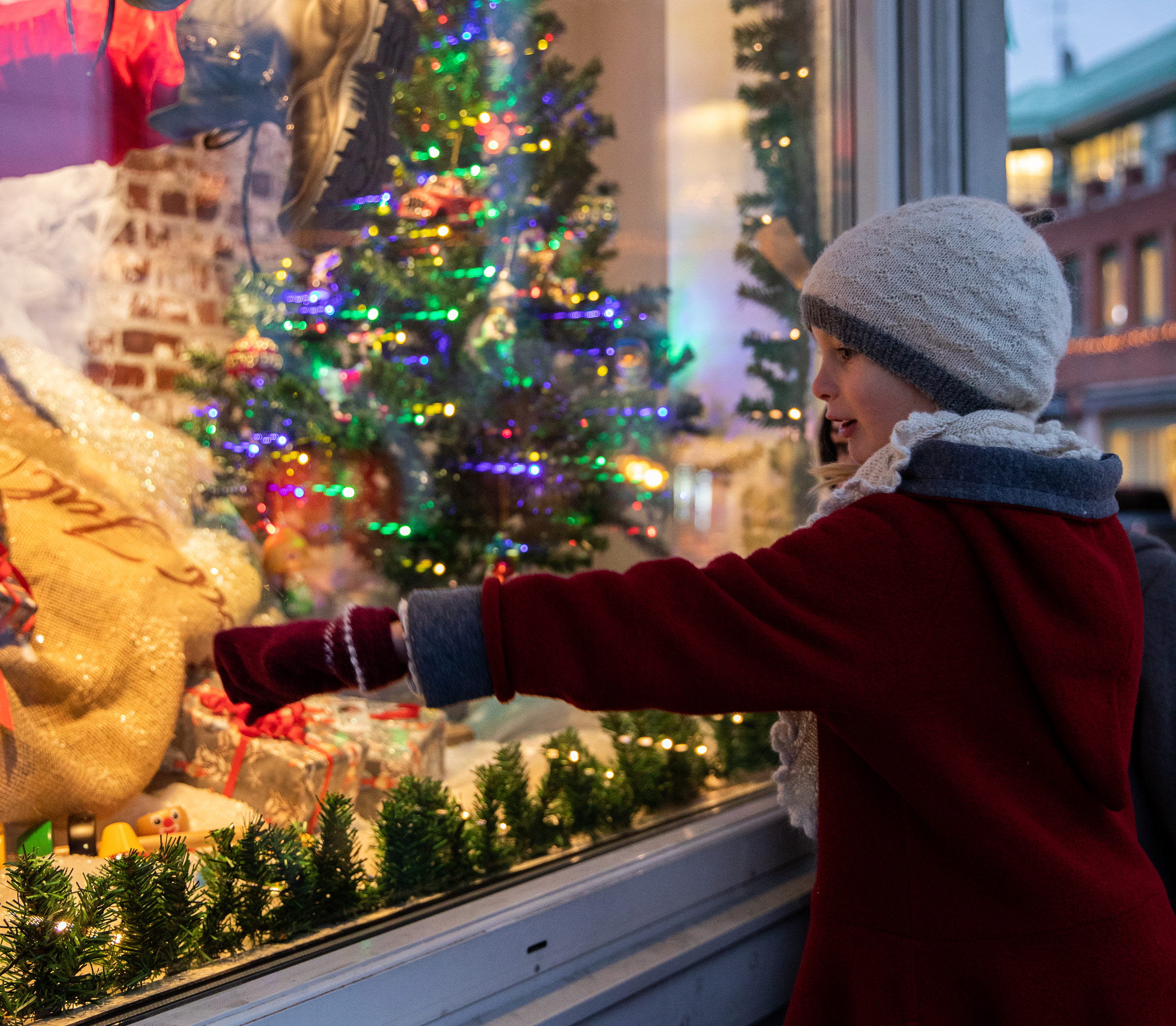 En flicka står och pekar in i ett julskyltat fönster