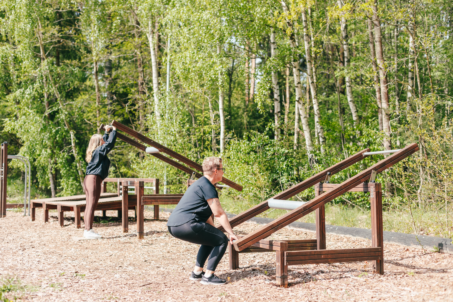 Två kvinnor tränar på ett utegym. 