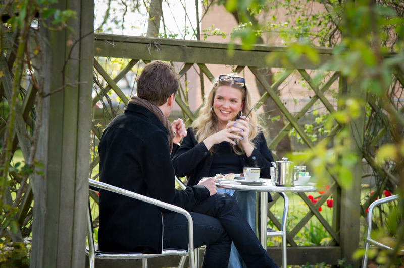 Två personer sitter vid ett bord och fikar utomhus