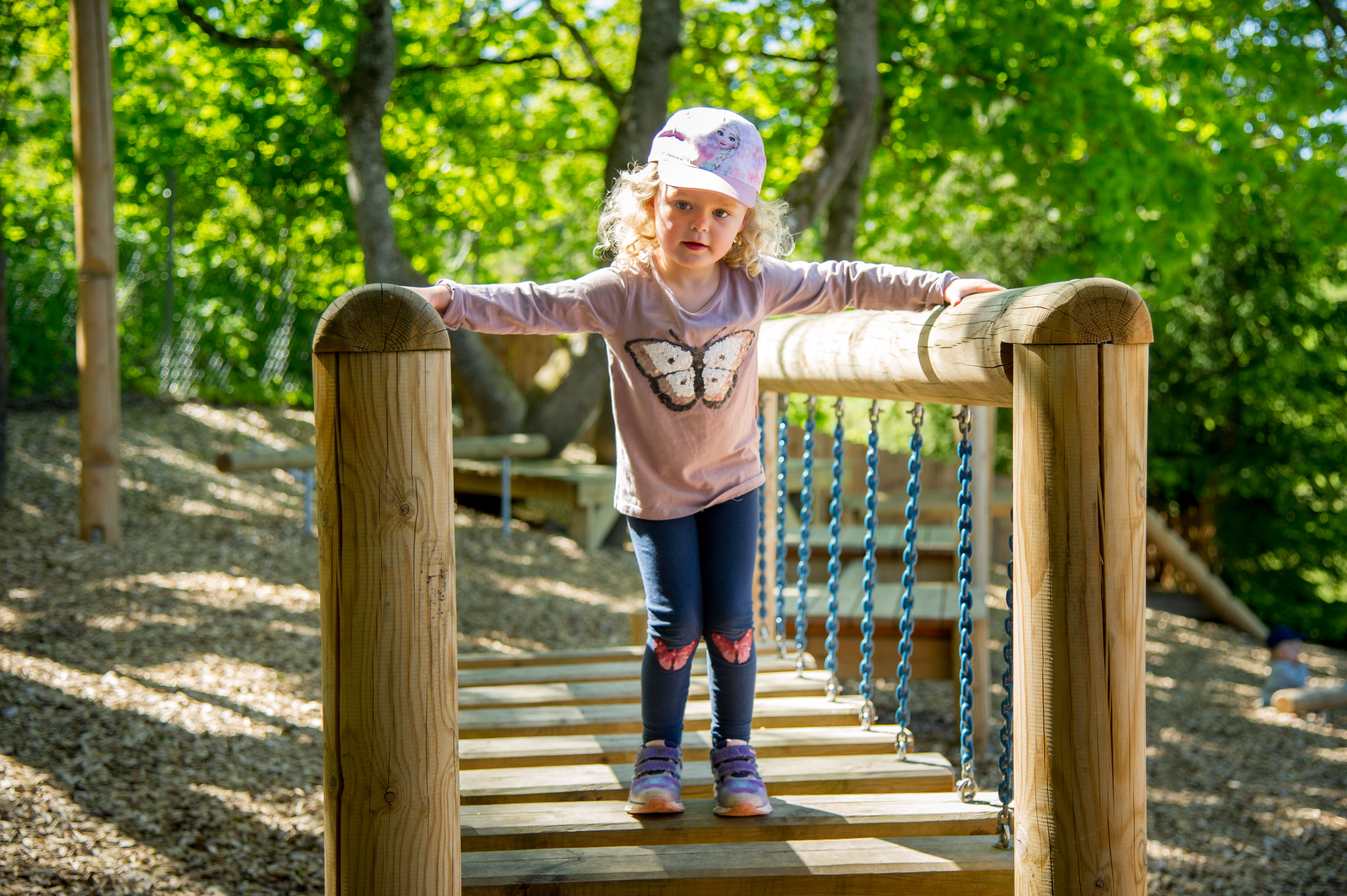 Ett barn på en gångbro på en lekplats.