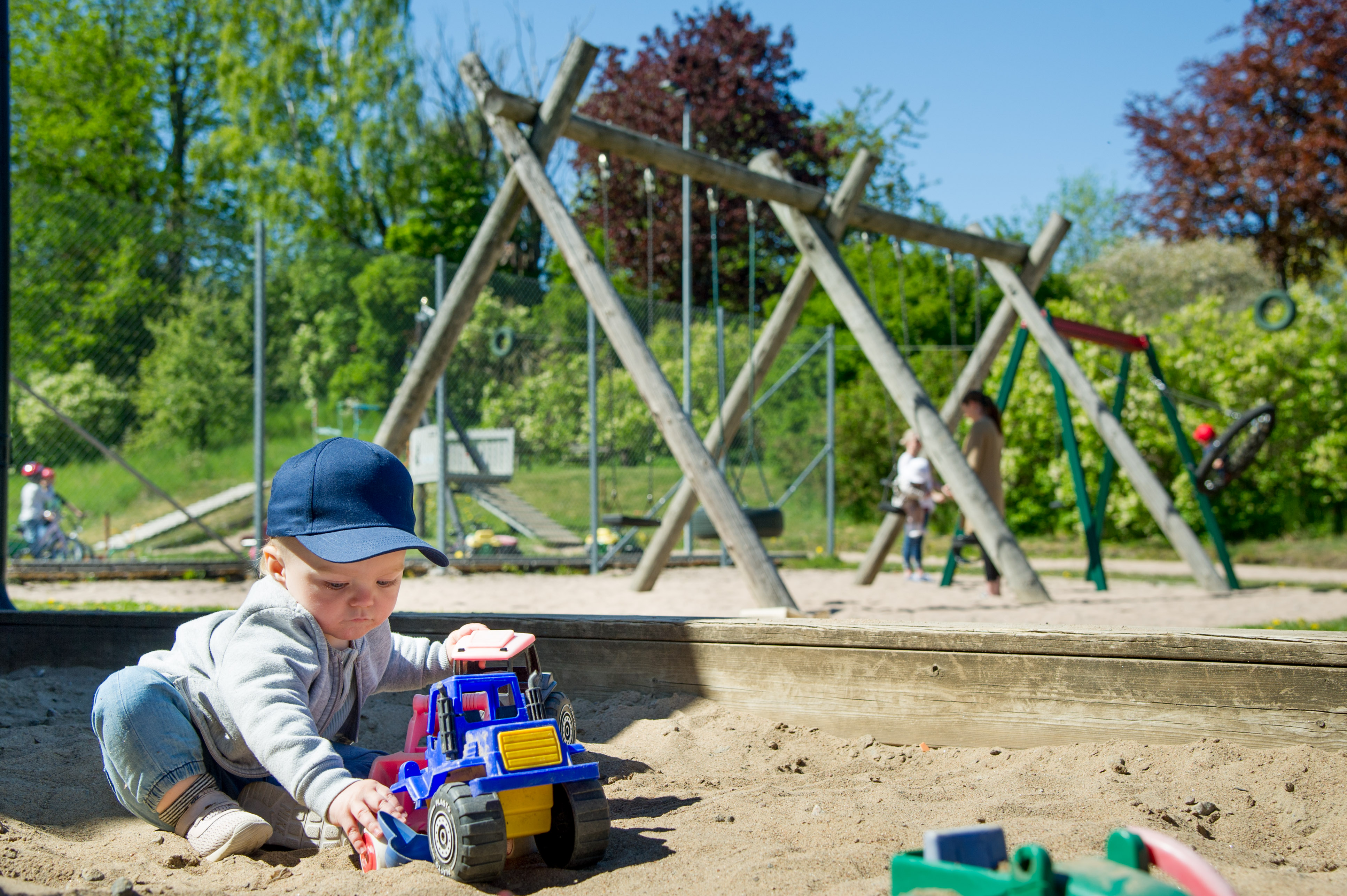 Ett barn som leker med sin bil i sin sandlåda
