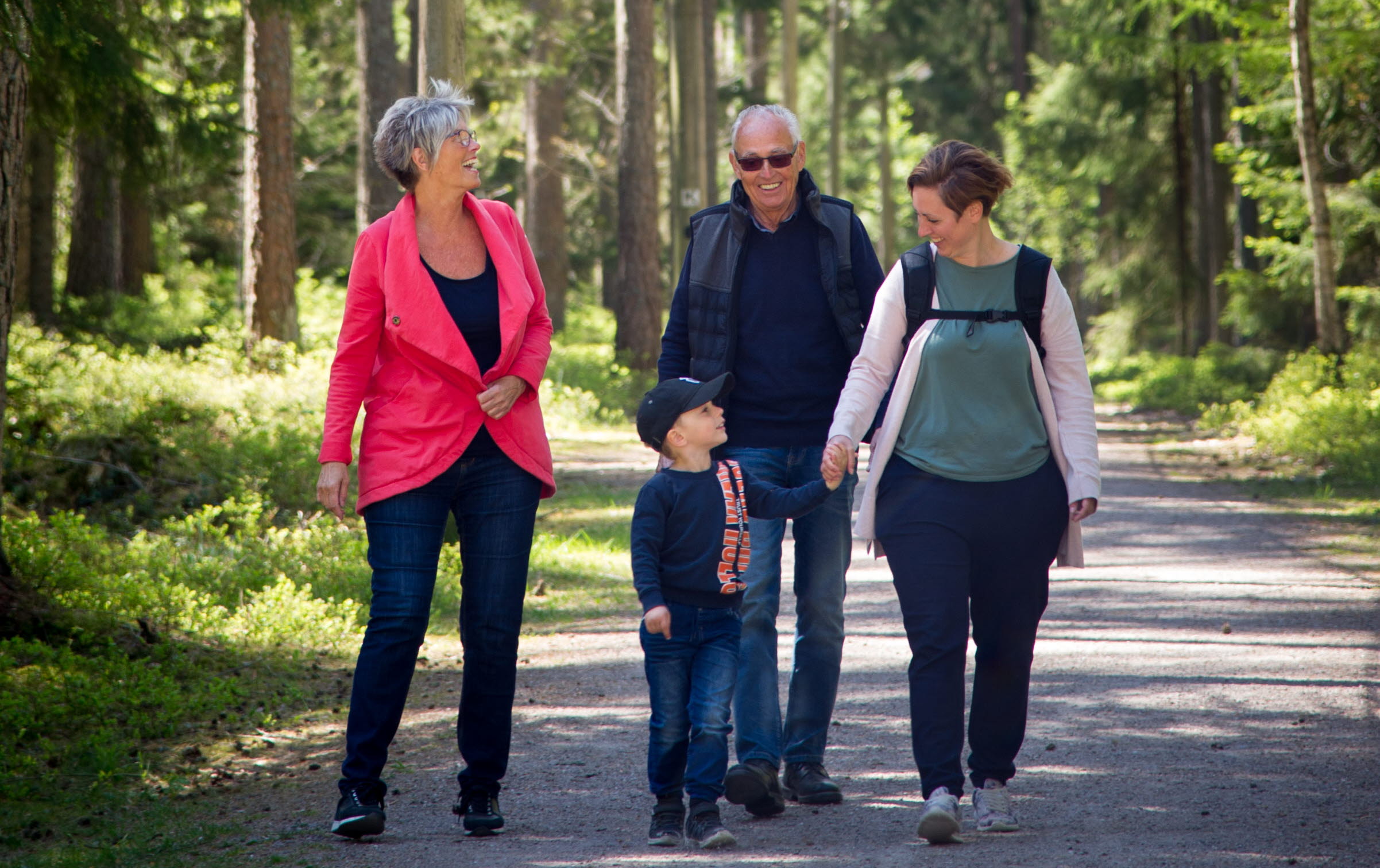 En familj är ute och går i skogen
