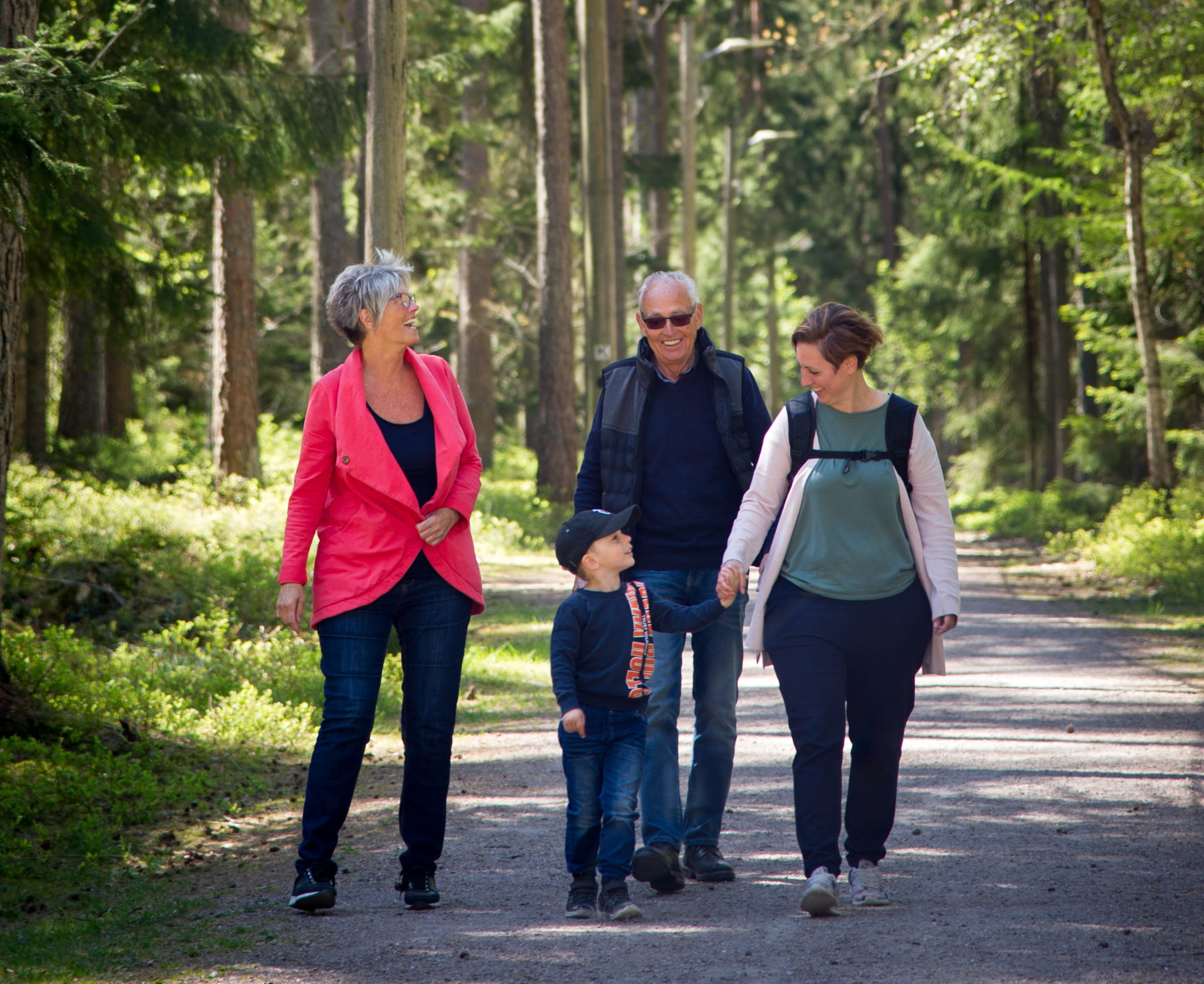 En familj är ute och går i skogen
