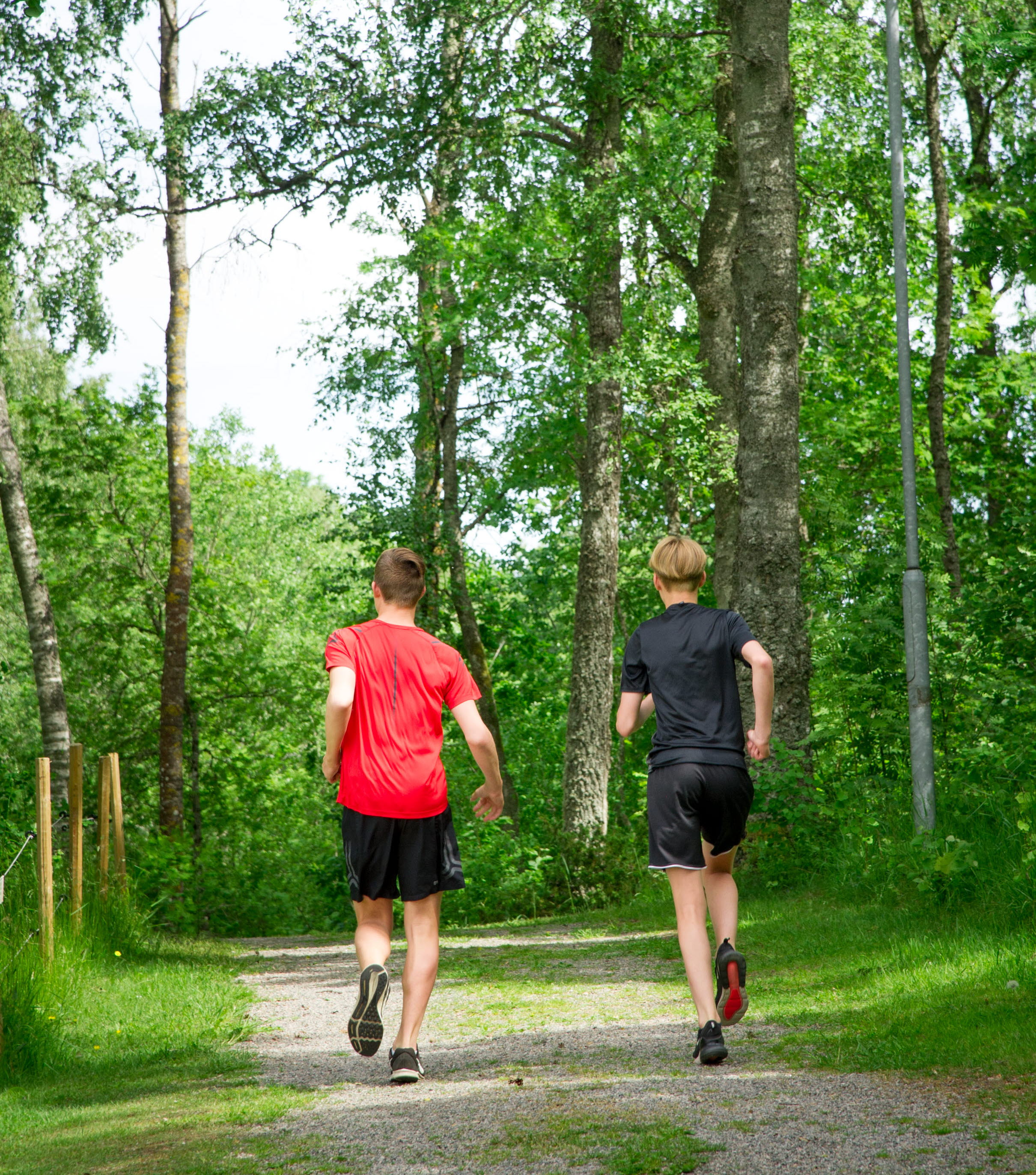 Två killar springer i ett motionsspår i naturen.