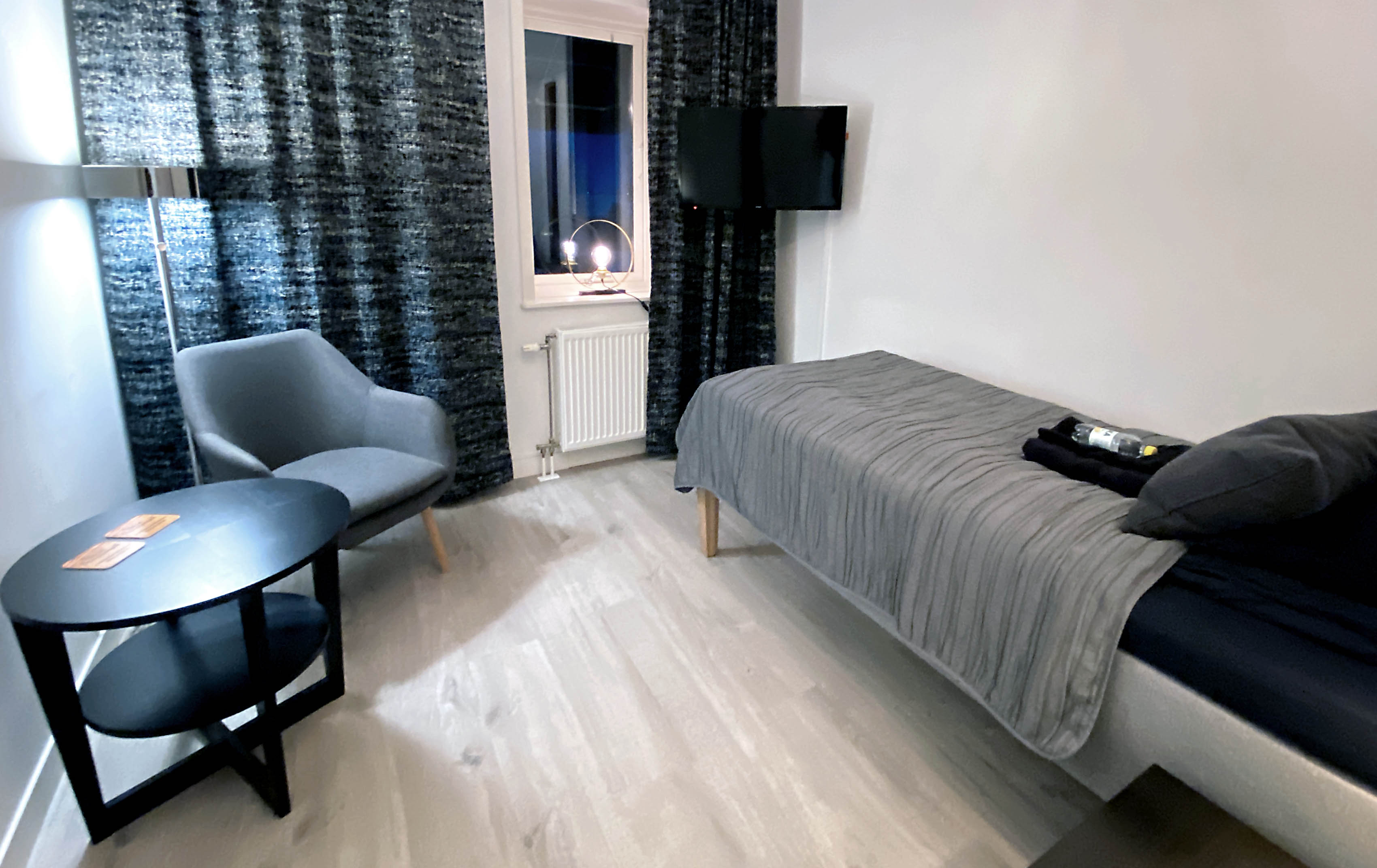 Ett rum med en säng, en fåtölj och ett bord.