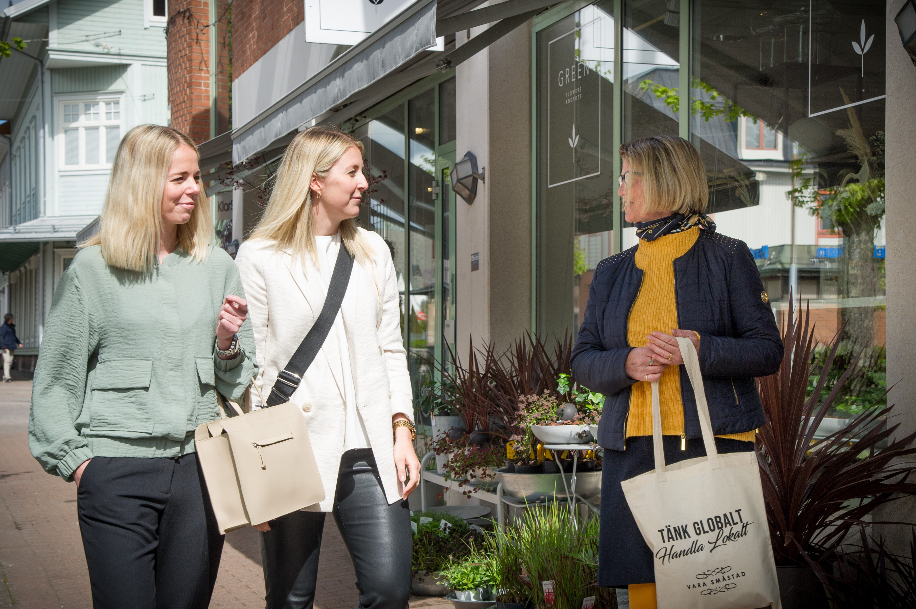 Three people walking outside a flower shop
