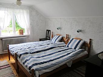 Två enkla bäddade sängar i randiga lakan, i ett ljust fint rum i stugan Stora Kåryd i Larv.