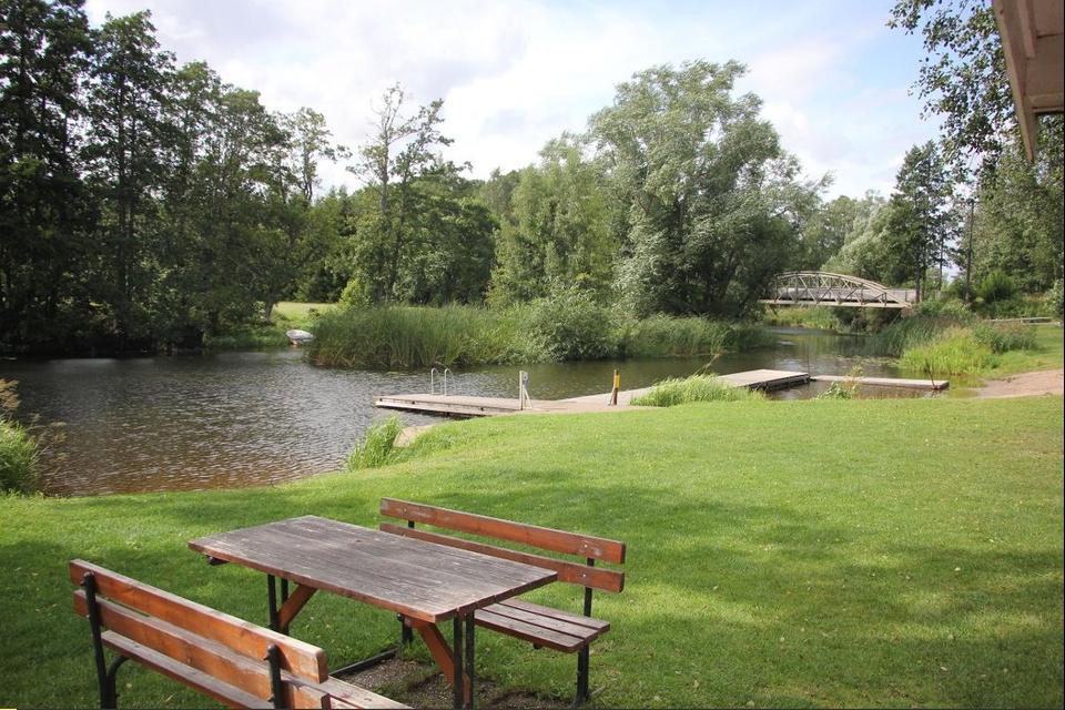 En badplats med gräs, brygga och några bänkar.