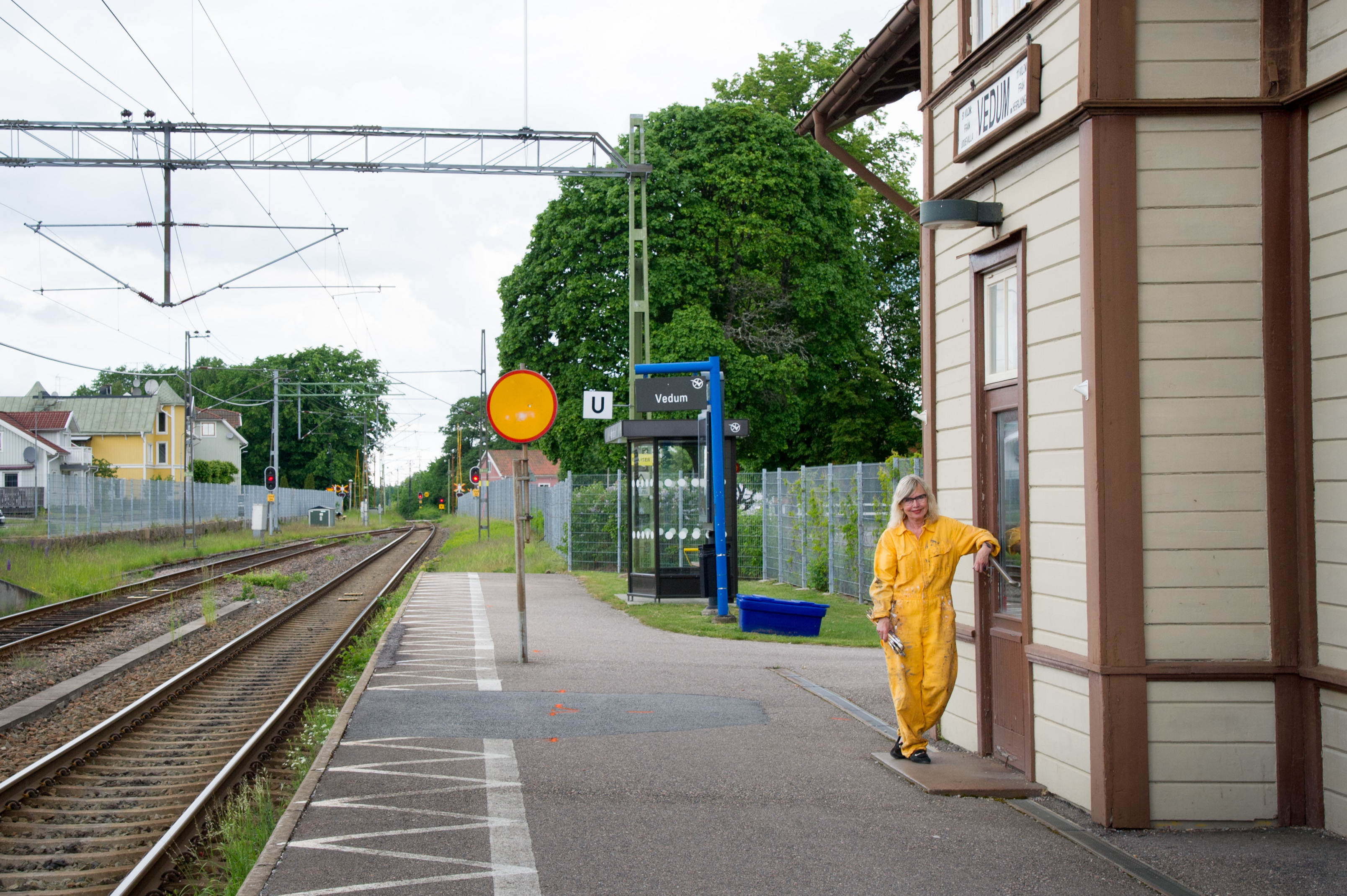 En kvinna i gula kläder står ensam på en tågstation